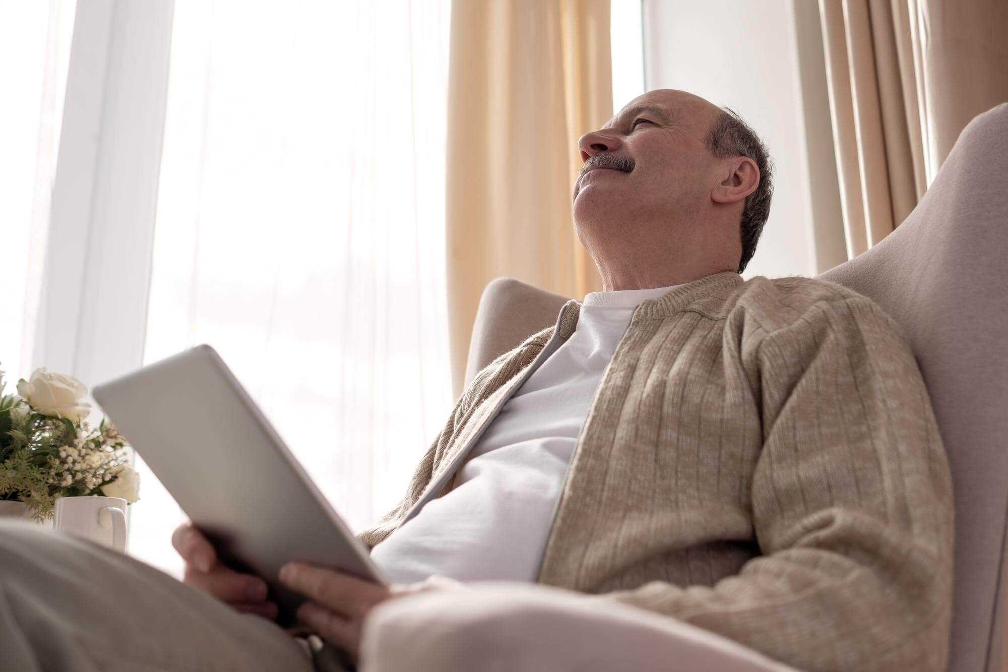 Middle-aged man leaning back in an armchair, head tilted back, eyes closed in relief