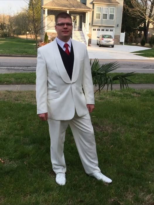 John King in a white suit standing in a front yard