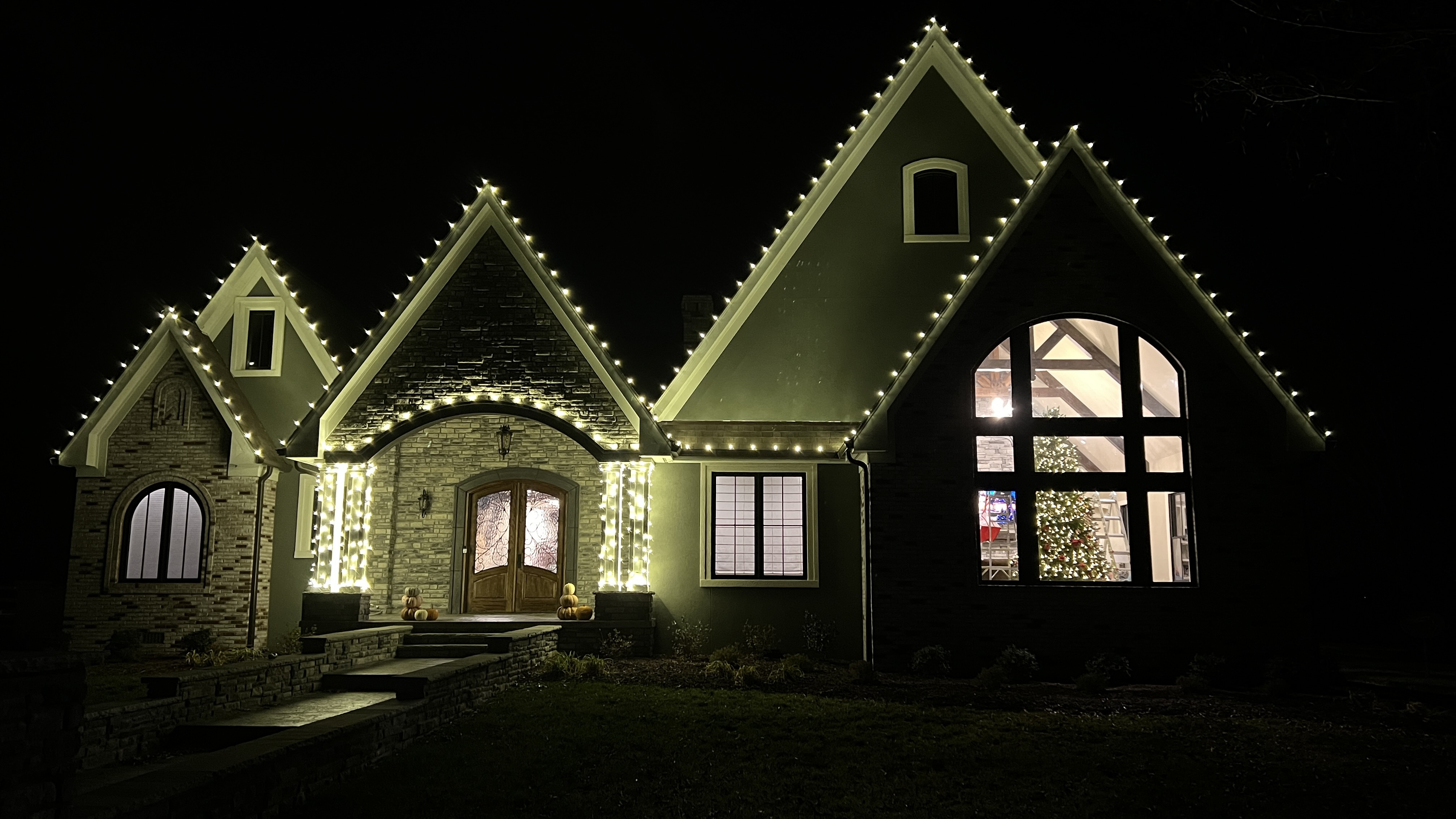 Stone home with warm white lights on every gable