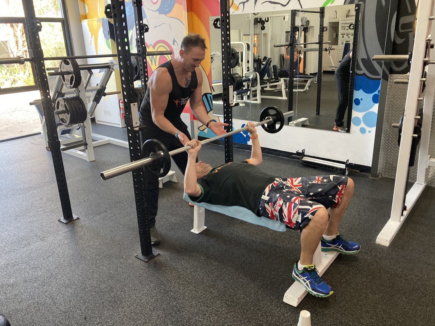 A gym member bench pressing with a spotter