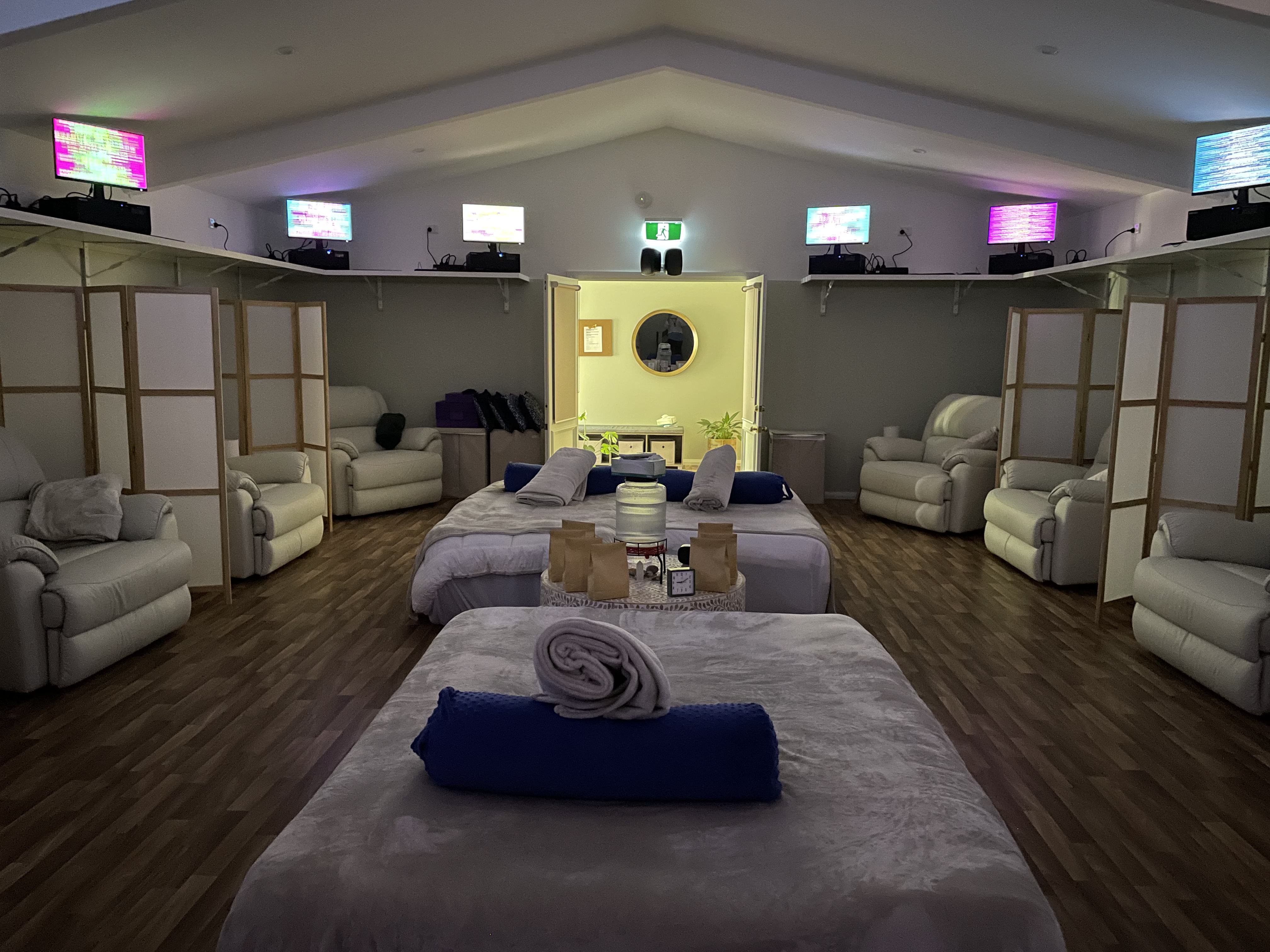 EE Wellness Within Energy Enhancement System lounge with comfortable recliners, massage tables, and scalar wave technology screens