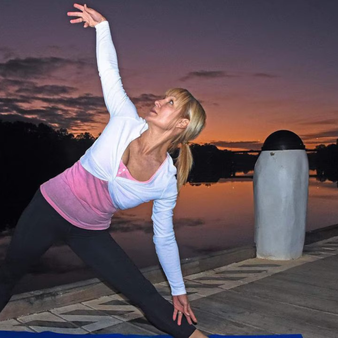 Lisa Allan, owner of EE Wellness Within, practicing yoga in extended side angle pose at sunset