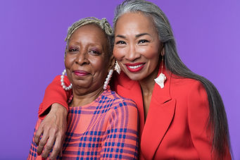 Two smiling older women embracing against a purple backdrop, one with grey locs and pearl hoop earrings, the other with long silver hair and a red blazer 3. NEVER STOP LEARNING Two smiling older women embracing against a purple backdrop, one with grey locs and pearl hoop earrings, the other with long silver hair and a red blazer 3. NEVER STOP LEARNING