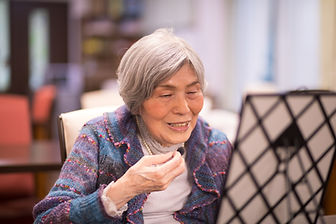 Smiling older woman with silver hair practicing a small instrument in front of a music stand Smiling older woman with silver hair practicing a small instrument in front of a music stand