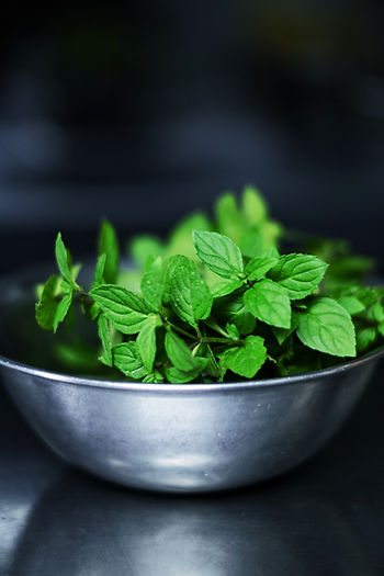 Bowl of fresh green mint leaves on a dark background