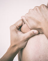 Close-up of hands massaging a person’s bare shoulder