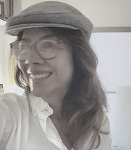 Smiling woman with long auburn hair wearing glasses, a grey flat cap and a white shirt Smiling woman with long auburn hair wearing glasses, a grey flat cap and a white shirt