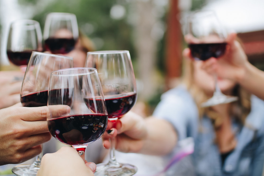 Close-up of friends clinking glasses of red wine together outdoors Close-up of friends clinking glasses of red wine together outdoors