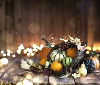 Wicker cornucopia spilling pumpkins, striped gourds and autumn leaves onto a rustic wooden table, with warm glowing lights in the background Wicker cornucopia spilling pumpkins, striped gourds and autumn leaves onto a rustic wooden table, with warm glowing lights in the background