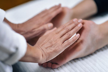 Close-up of a reiki practitioner’s hands hovering over a person’s hands resting on a white towel during an energy healing session Close-up of a reiki practitioner’s hands hovering over a person’s hands resting on a white towel during an energy healing session