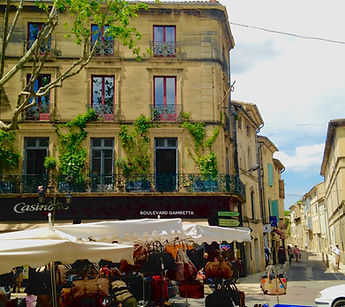 Outdoor market stalls selling leather bags beneath elegant stone buildings with wrought-iron balconies on Boulevard Gambetta in a French town Outdoor market stalls selling leather bags beneath elegant stone buildings with wrought-iron balconies on Boulevard Gambetta in a French town