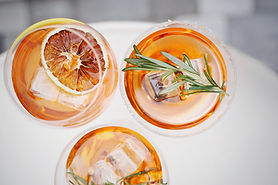 Overhead view of three amber zero-proof cocktails with ice, garnished with a dried orange slice and fresh rosemary sprigs Overhead view of three amber zero-proof cocktails with ice, garnished with a dried orange slice and fresh rosemary sprigs