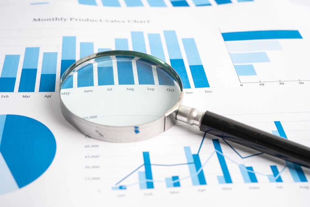 Magnifying glass examining printed marketing performance charts during a digital marketing audit