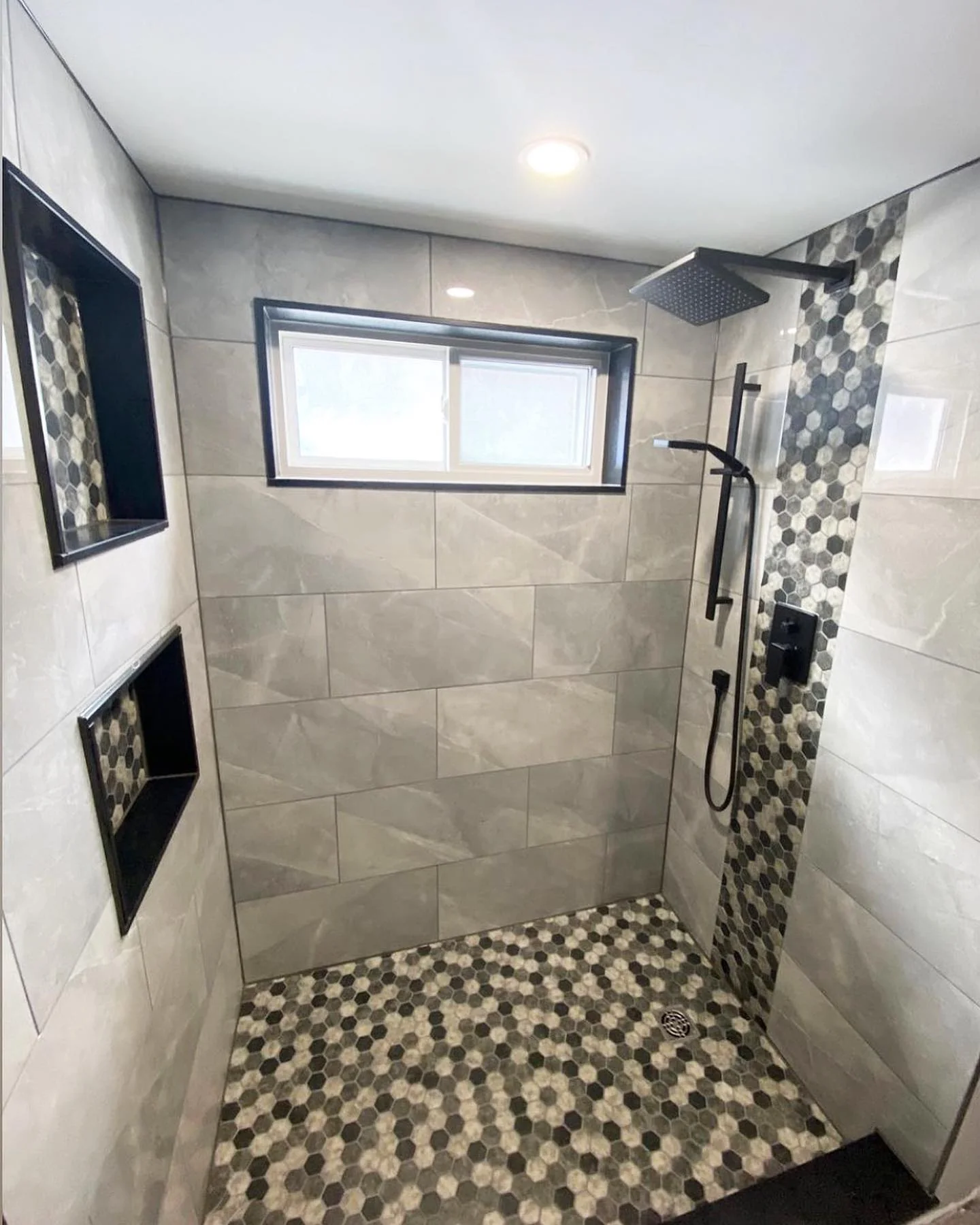 Large custom shower with grey tile and mosaic floor