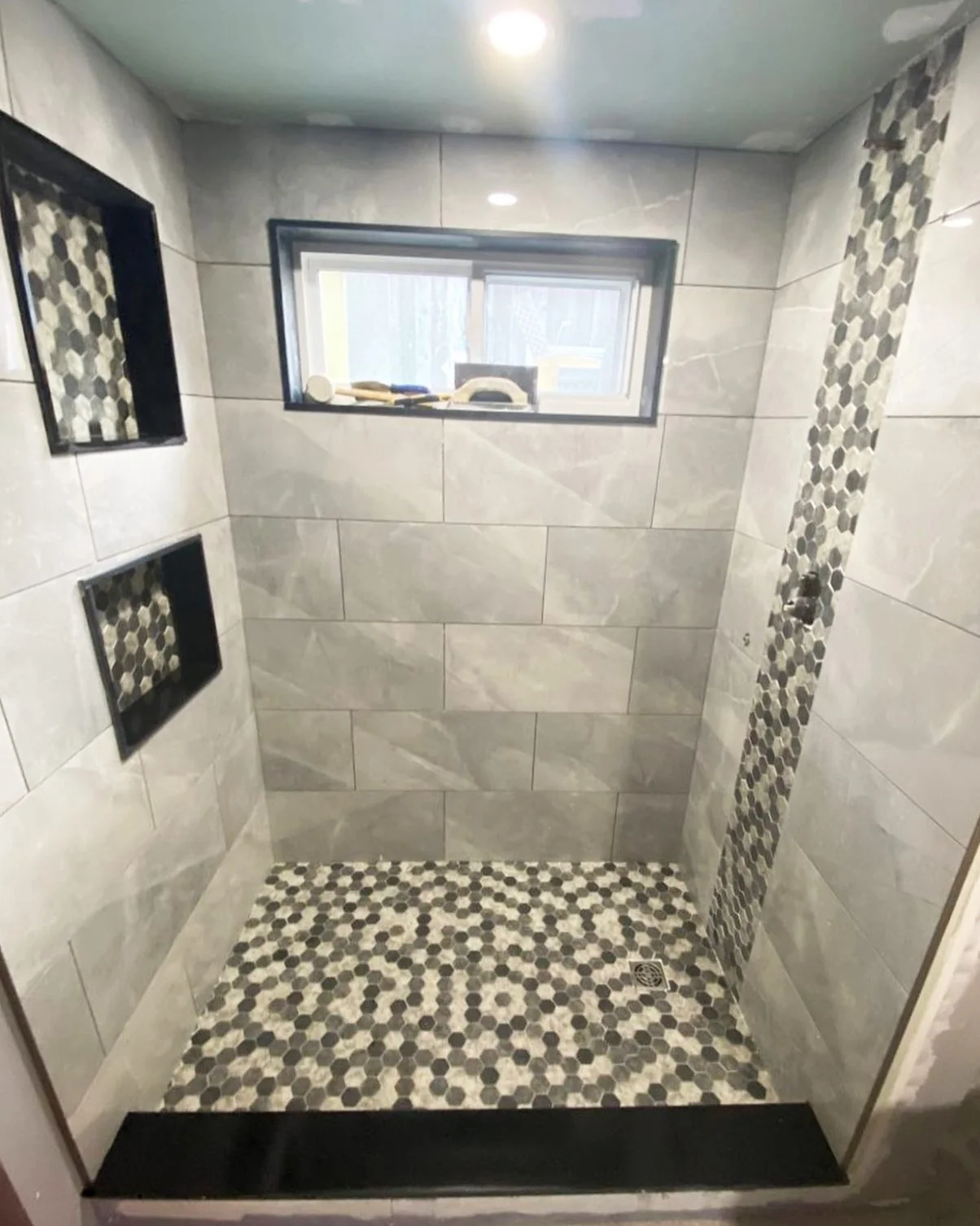 Grey tile shower with mosaic floor