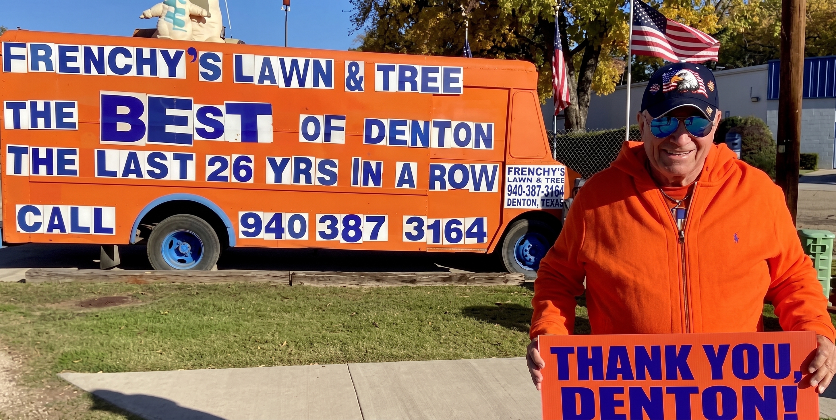 Frenchy holding a thank-you sign in front of an orange Frenchy's Lawn & Tree truck