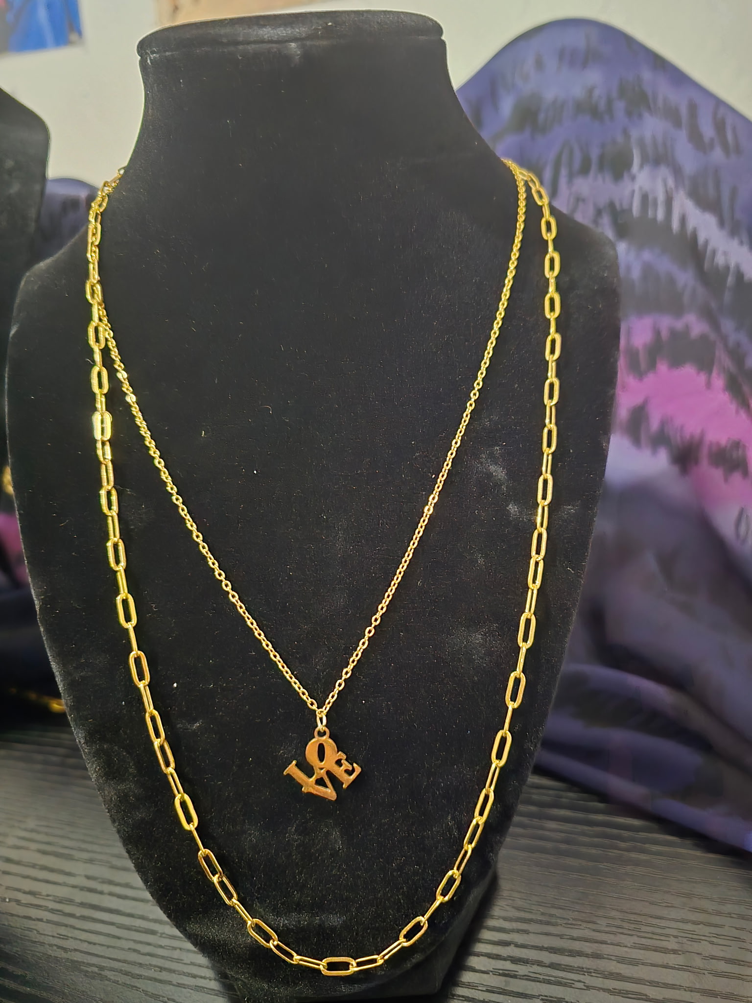 Gold paperclip permanent necklace with love charm on a display bust Payson AZ