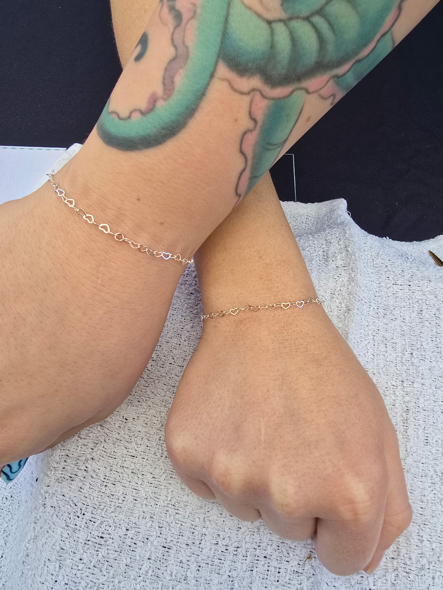Matching permanent bracelets gold heart link on two wrists Arizona