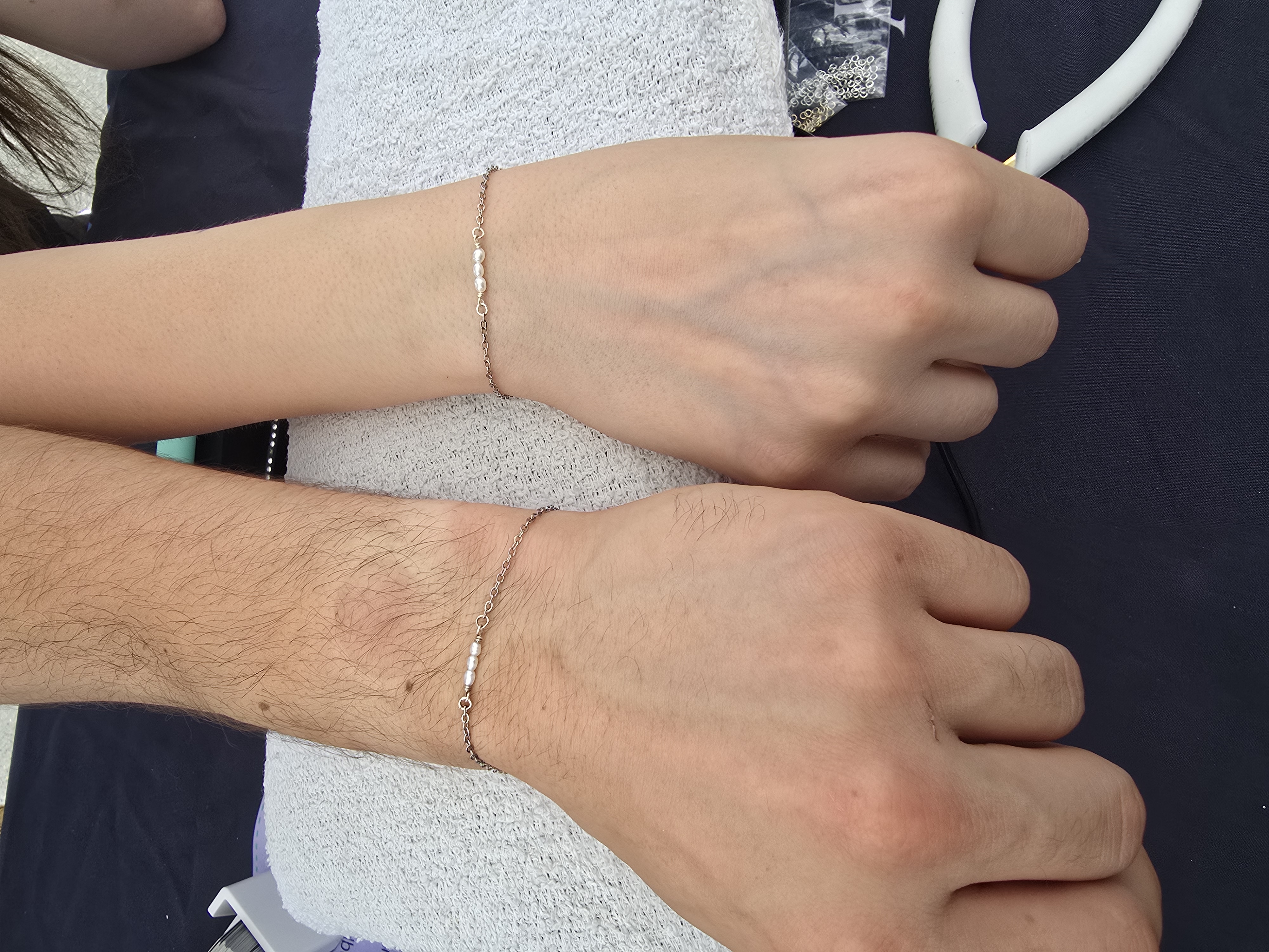 Two friends' wrists side by side with matching welded friendship bracelets