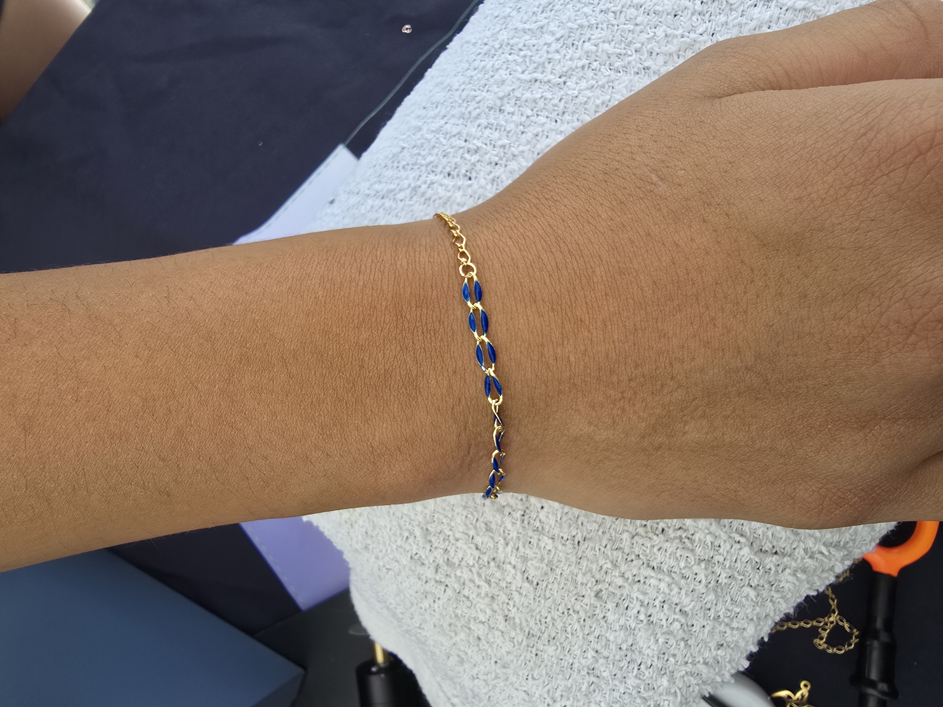 Gold chain and navy enamel chain mixed into one permanent bracelet on a wrist Arizona