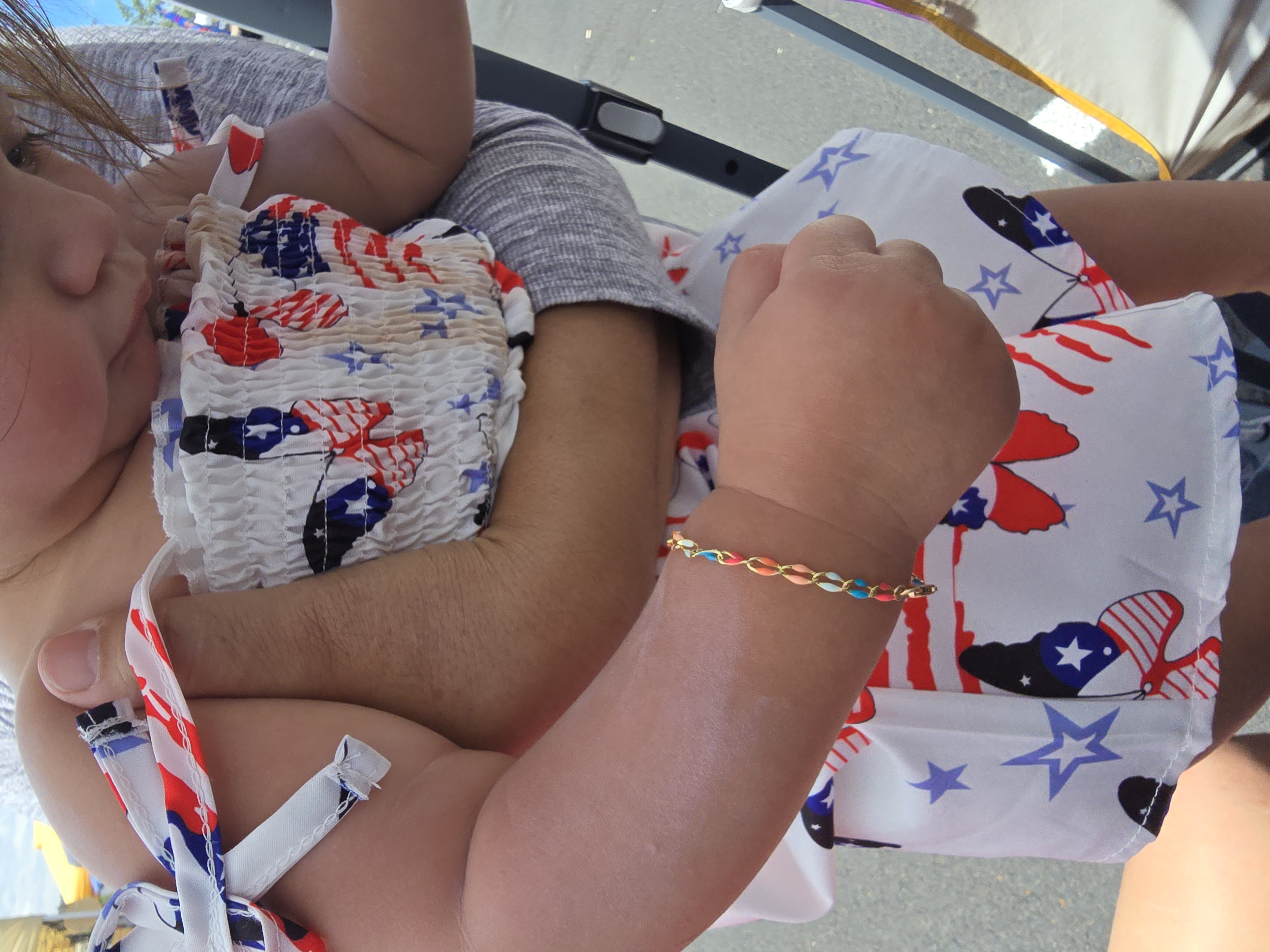 Baby wearing a tiny clasped bracelet in a patriotic outfit Payson AZ