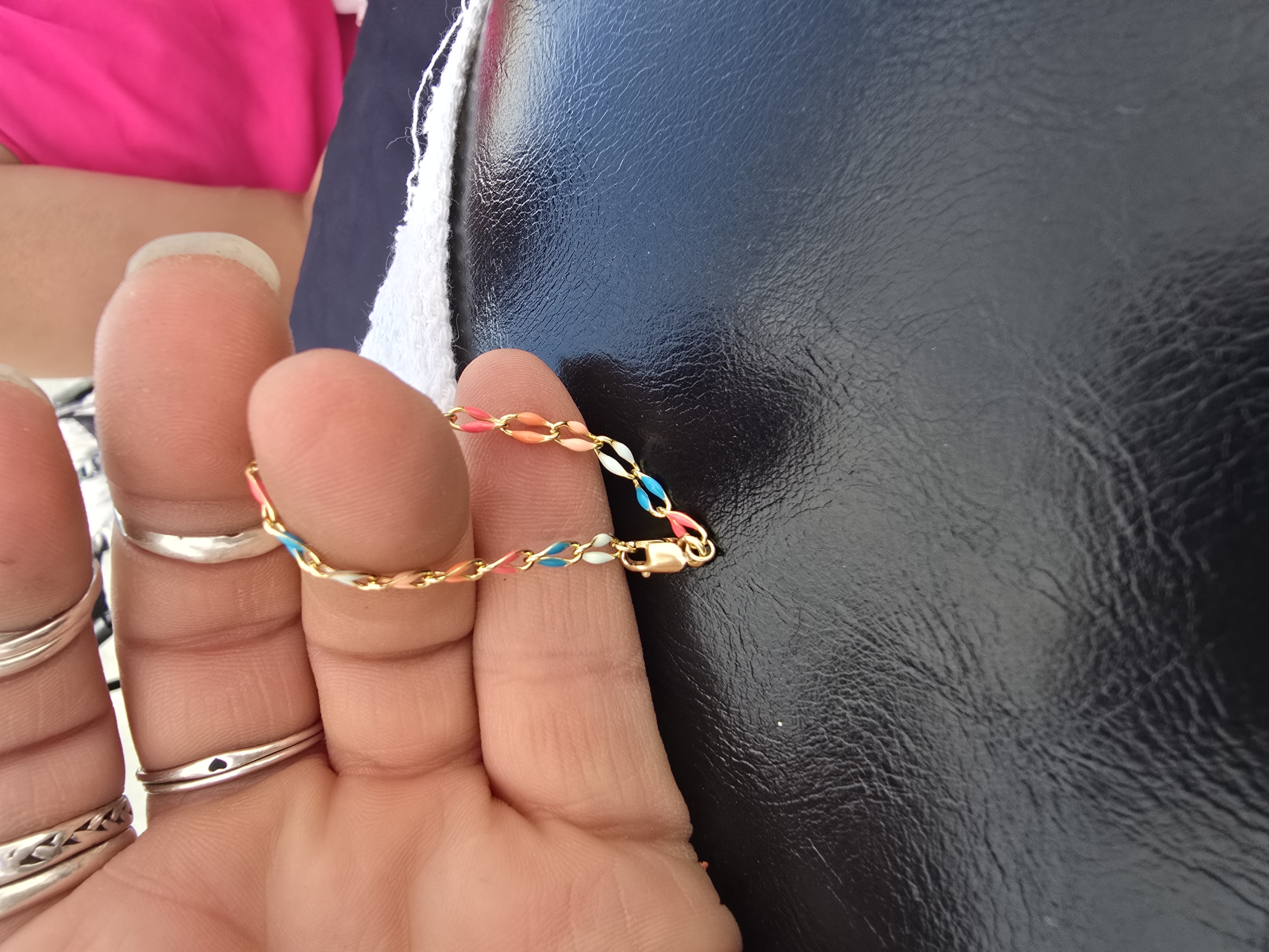Lobster clasp on a colorful enamel kids bracelet held in fingers