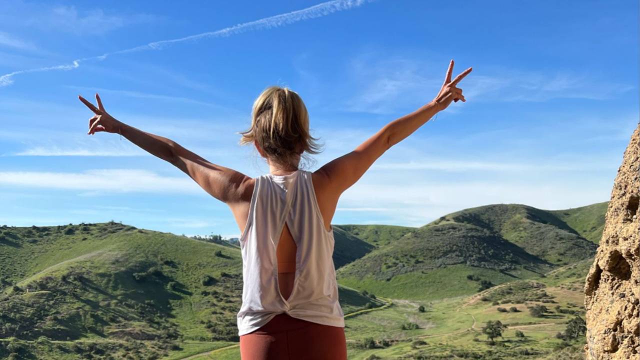 Woman with arms raised on a hilltop