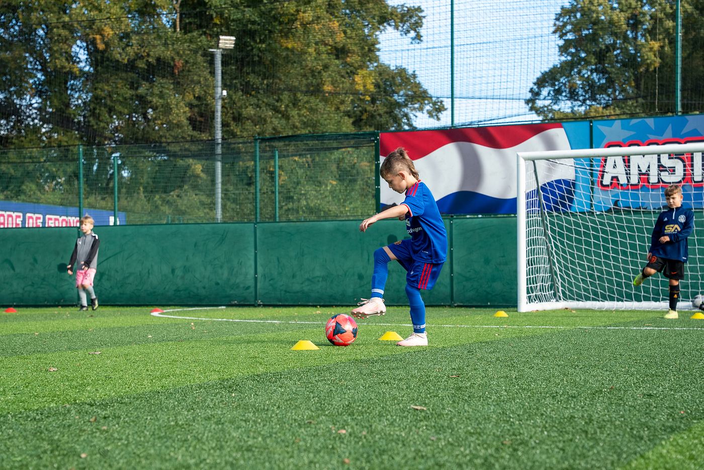 A young player dribbling through cones