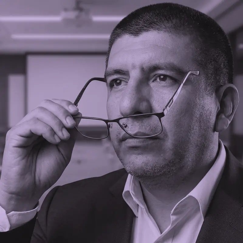 Luis Betancur, pensativo, sostiene sus gafas en una sala de juntas