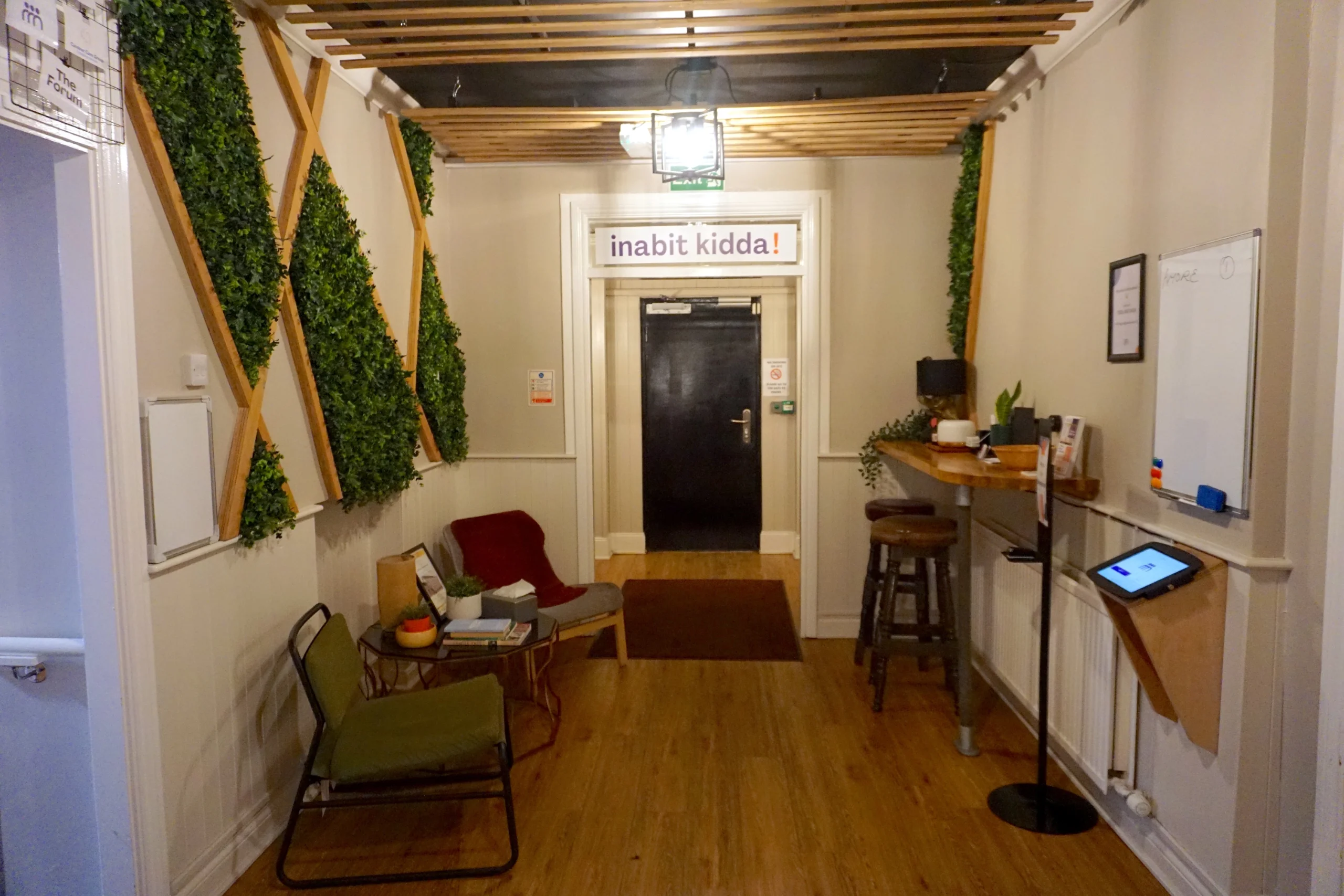 Reception at the Maggie O'Neill Centre, with living-wall panels, chairs and a slatted oak ceiling