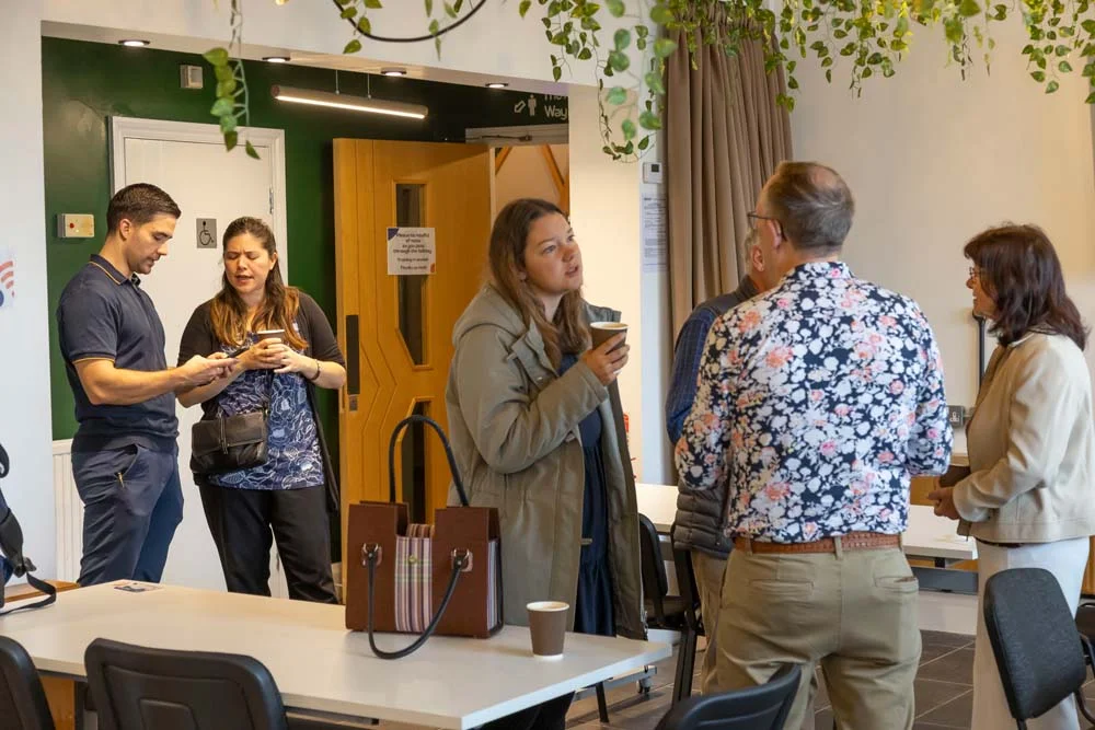People chatting with drinks at a networking event in the Grove at the Maggie O'Neill Centre