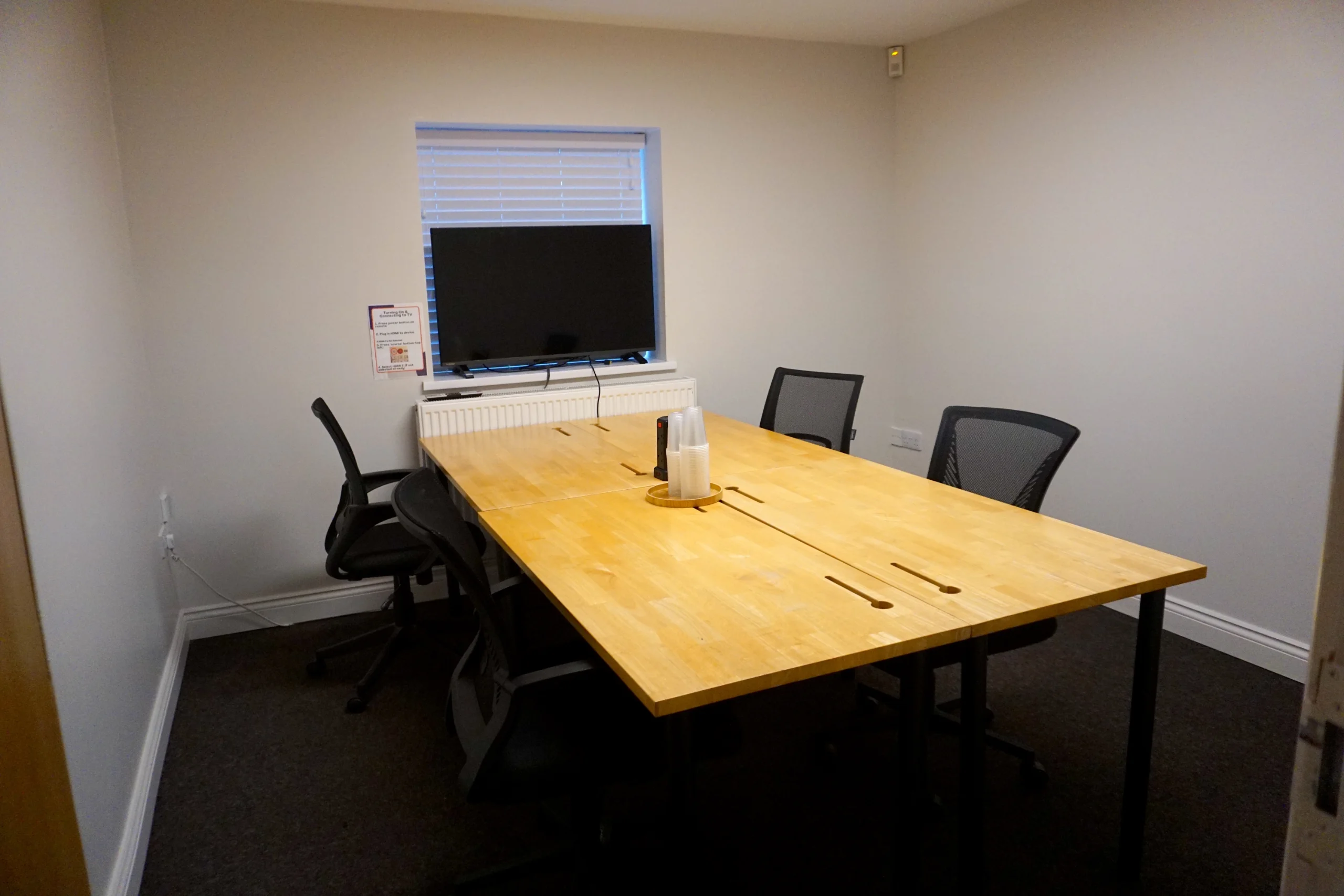 The Pod meeting room at the Maggie O'Neill Centre, an oak table for 4 with a wall screen