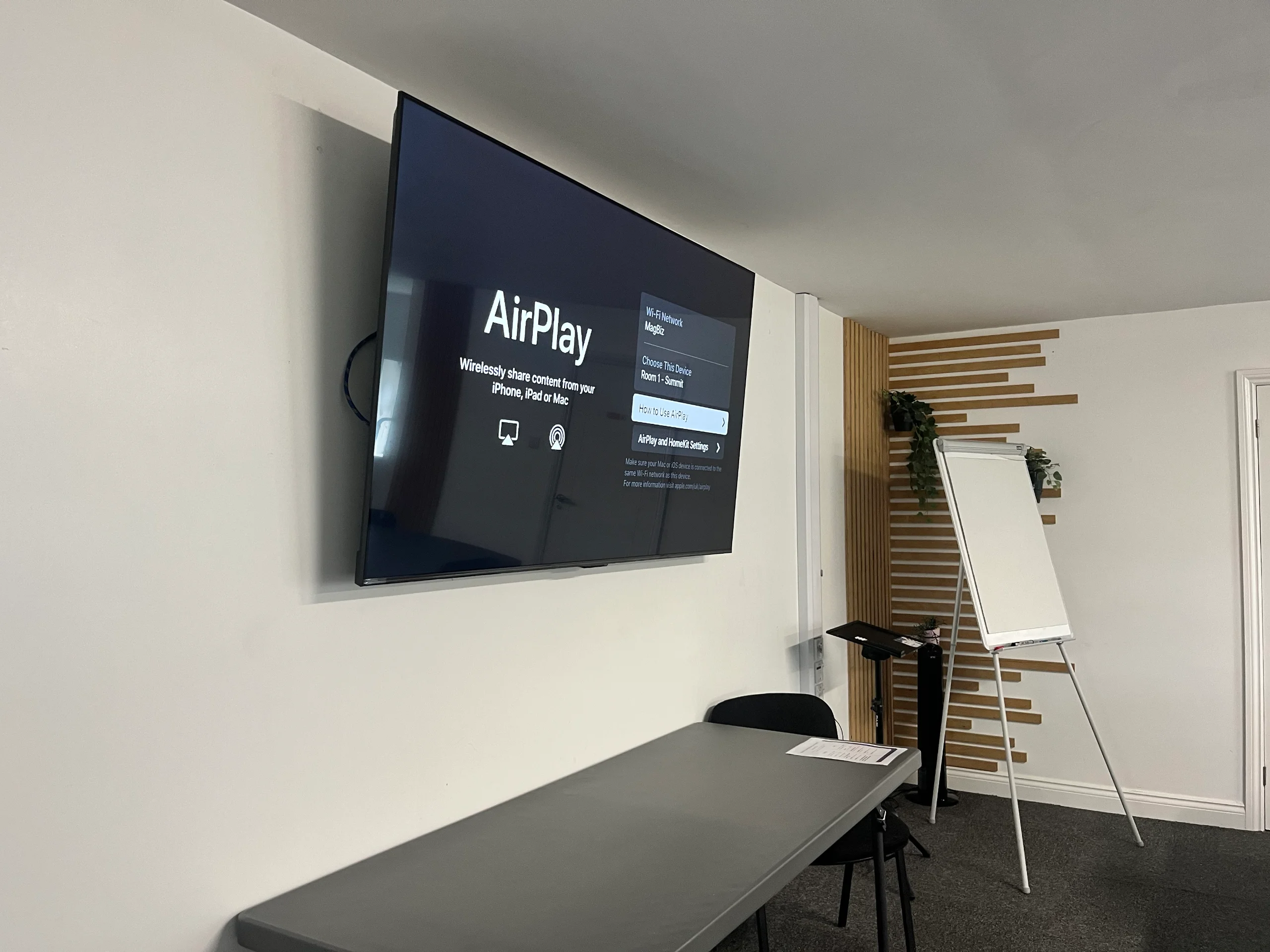 The screen in the Summit at the Maggie O'Neill Centre showing AirPlay, beside a flipchart