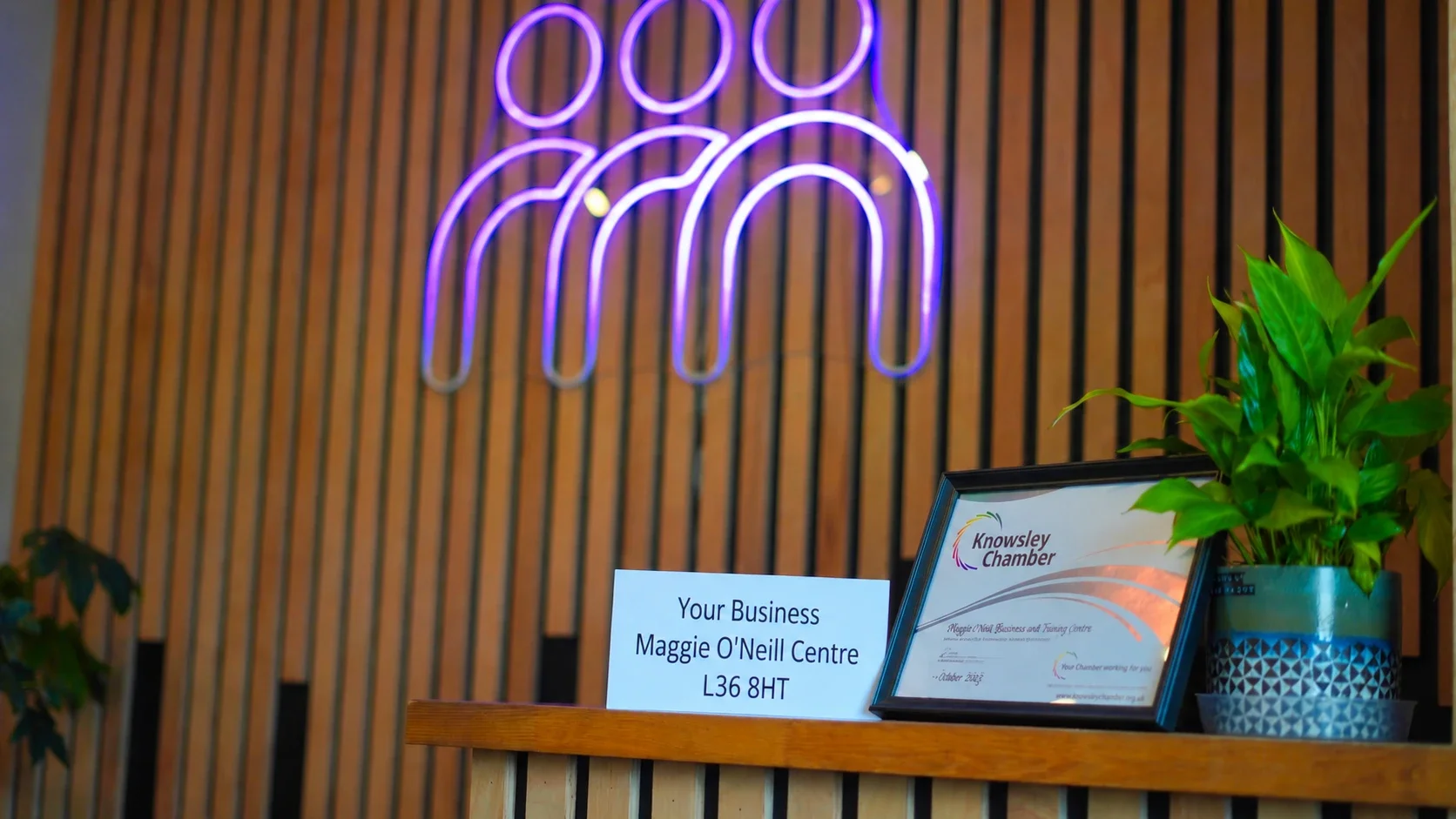 Post for a virtual office client on the shelf under the neon logo at the Maggie O'Neill Centre
