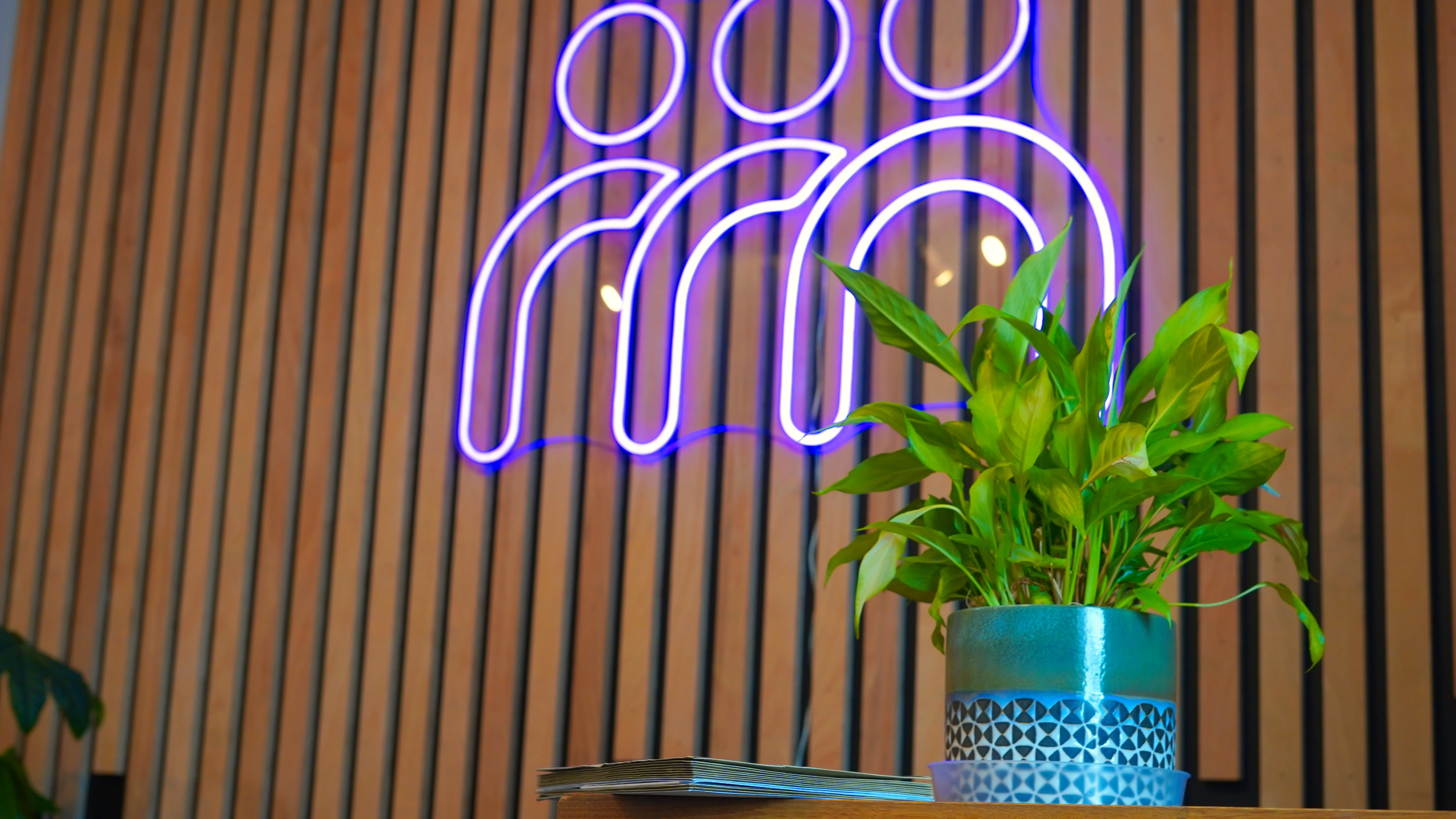 A stack of client post on the shelf under the neon logo at the Maggie O'Neill Centre