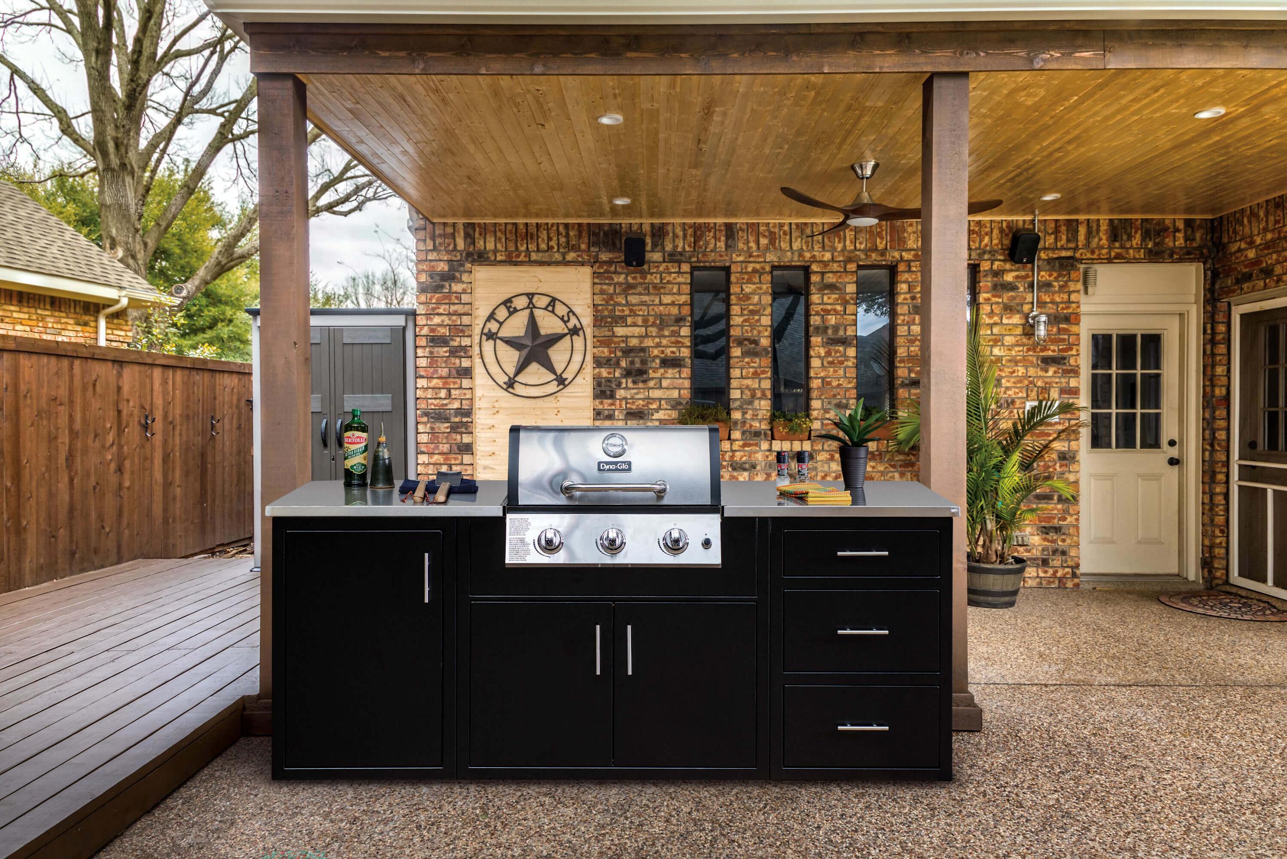 Black aluminum gas grill cabinet on a wooden deck under a covered patio