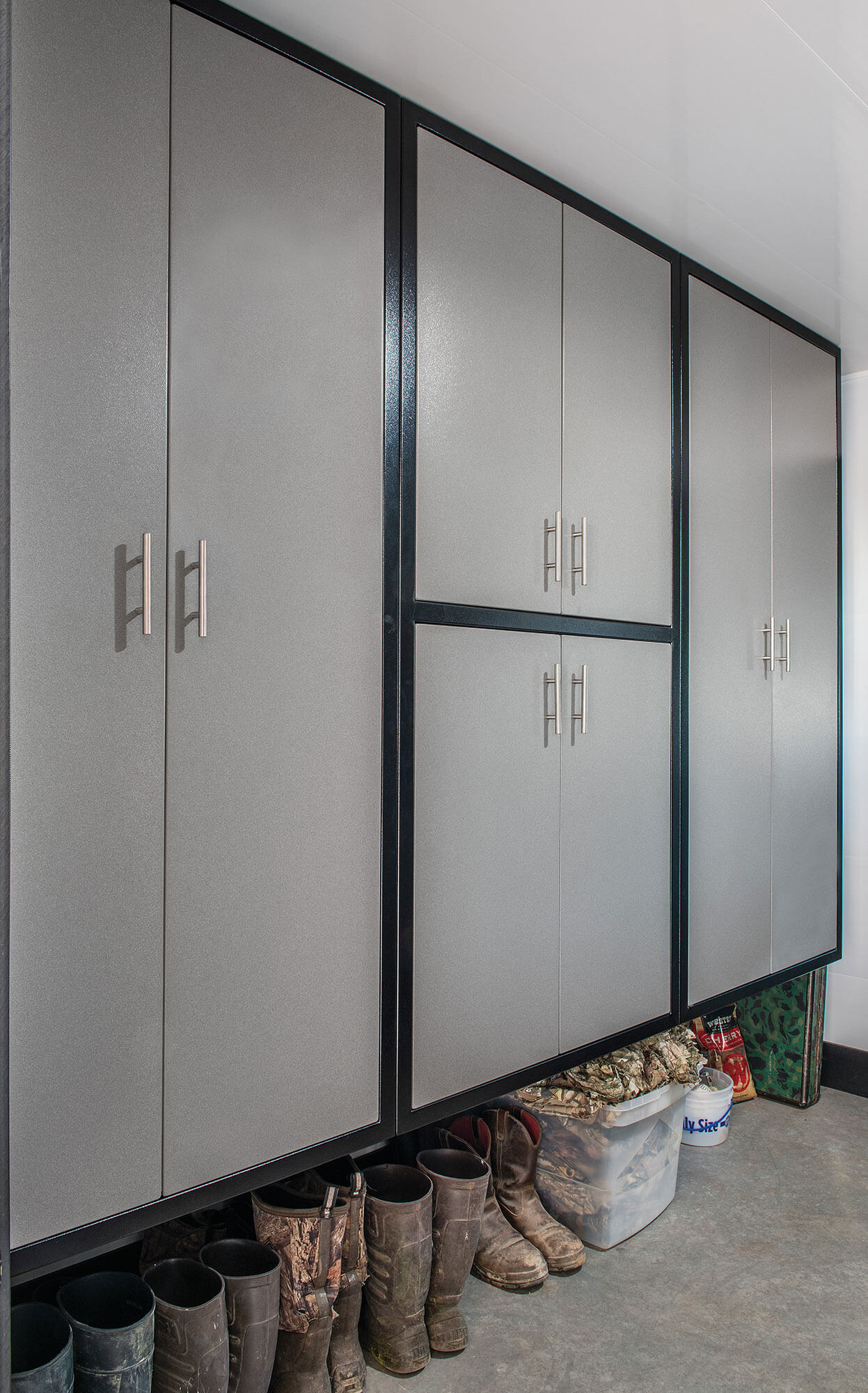 Tall gray and black aluminum mudroom closets with boots stored underneath