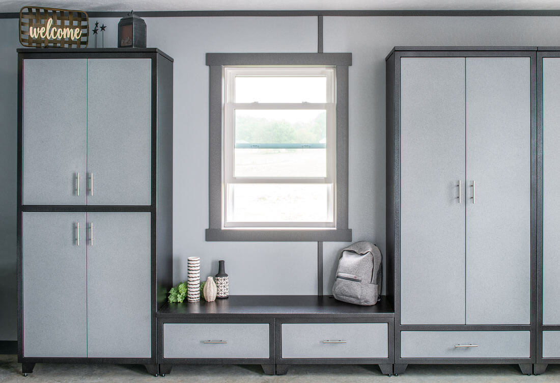 Silver and blue aluminum mudroom closets on either side of a boot bench under a window