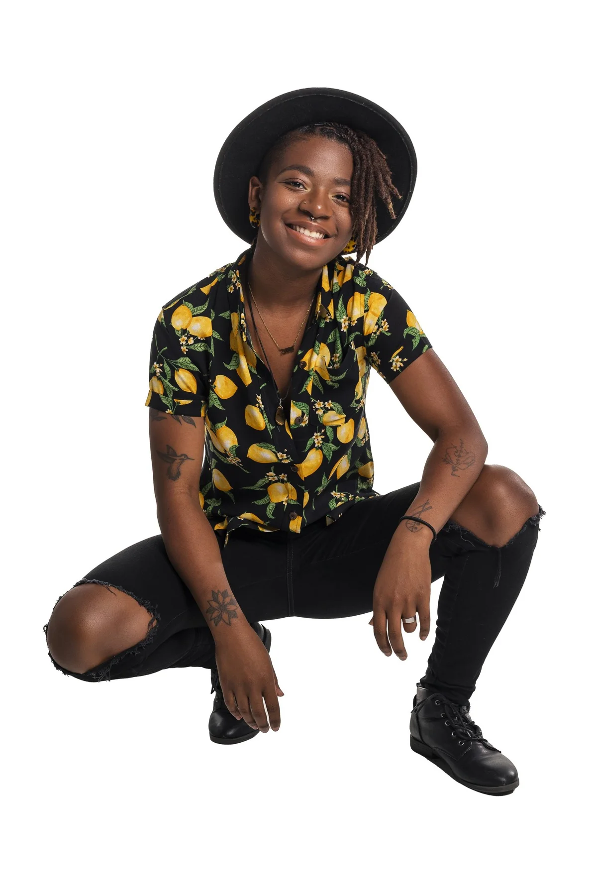 Studio fashion portrait of a smiling model in a patterned shirt and black hat