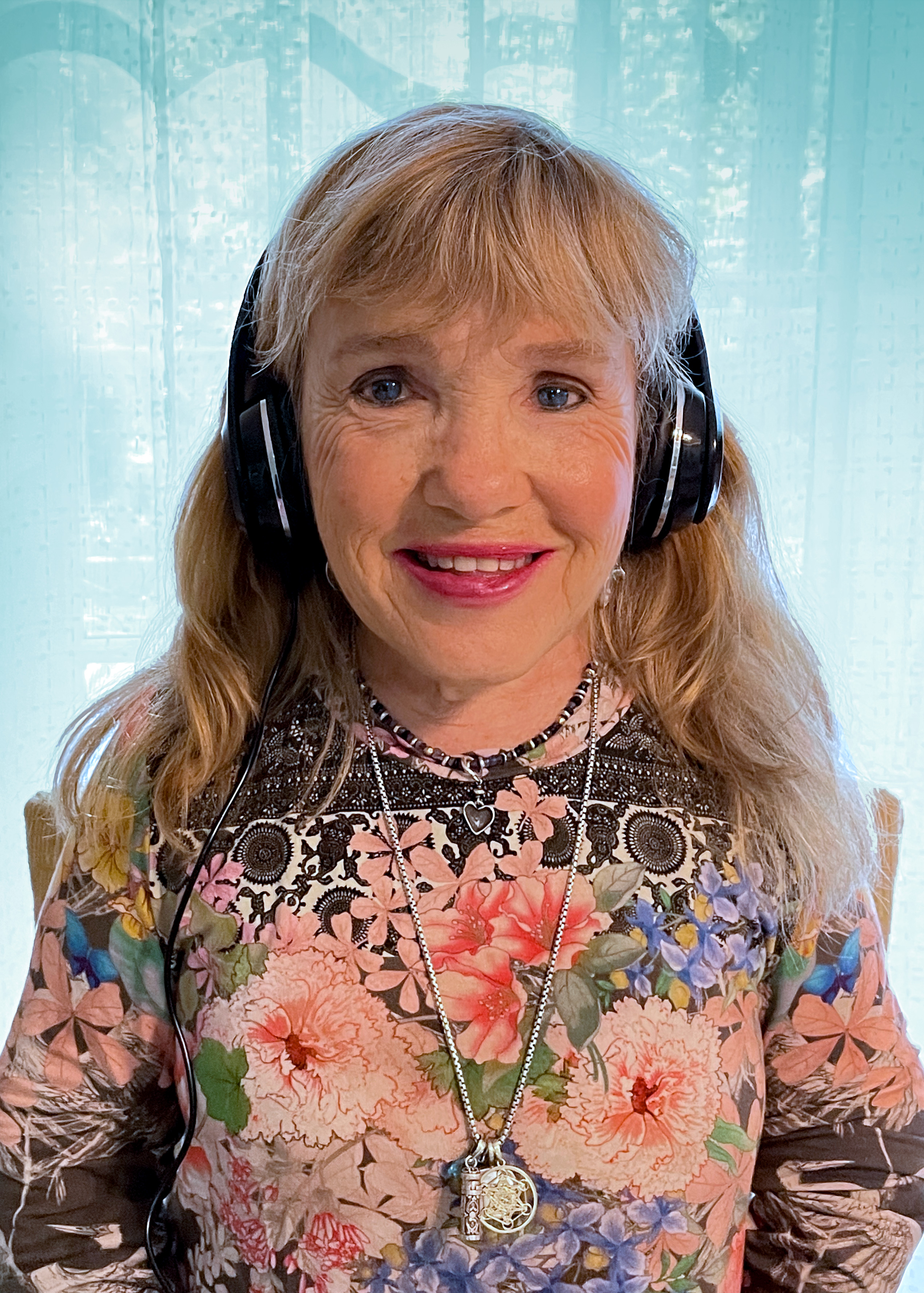 Photo of Peggy O’Neill with a paid or headphones on, wearing a floral shirt