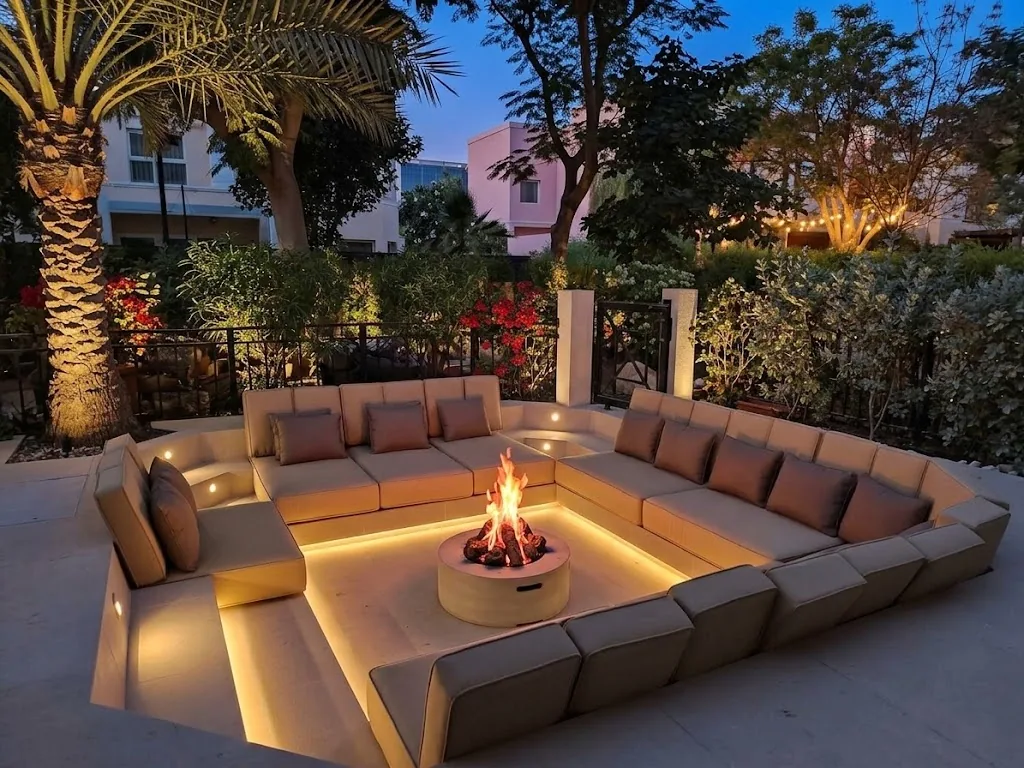 Sunken outdoor lounge around a lit fire pit in the evening