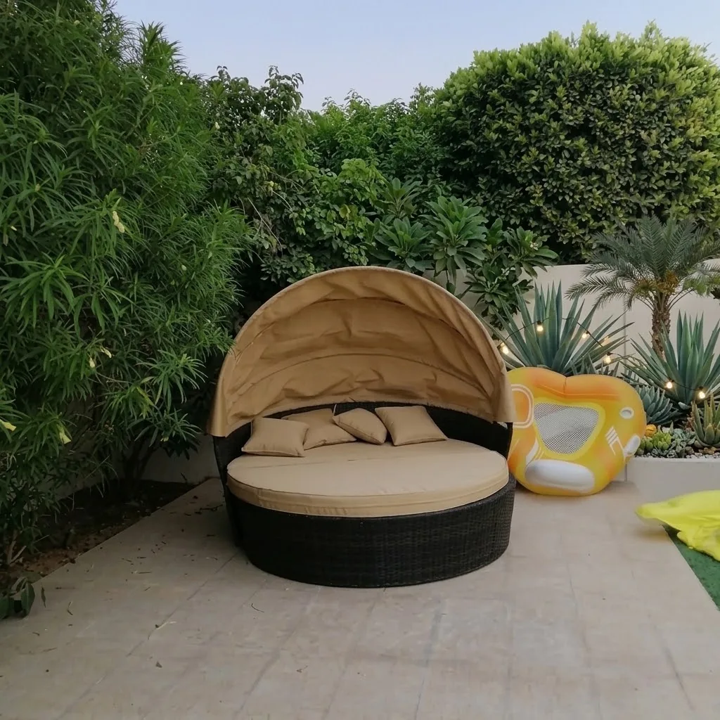 Round wicker daybed with a canopy and beige cushions in a garden