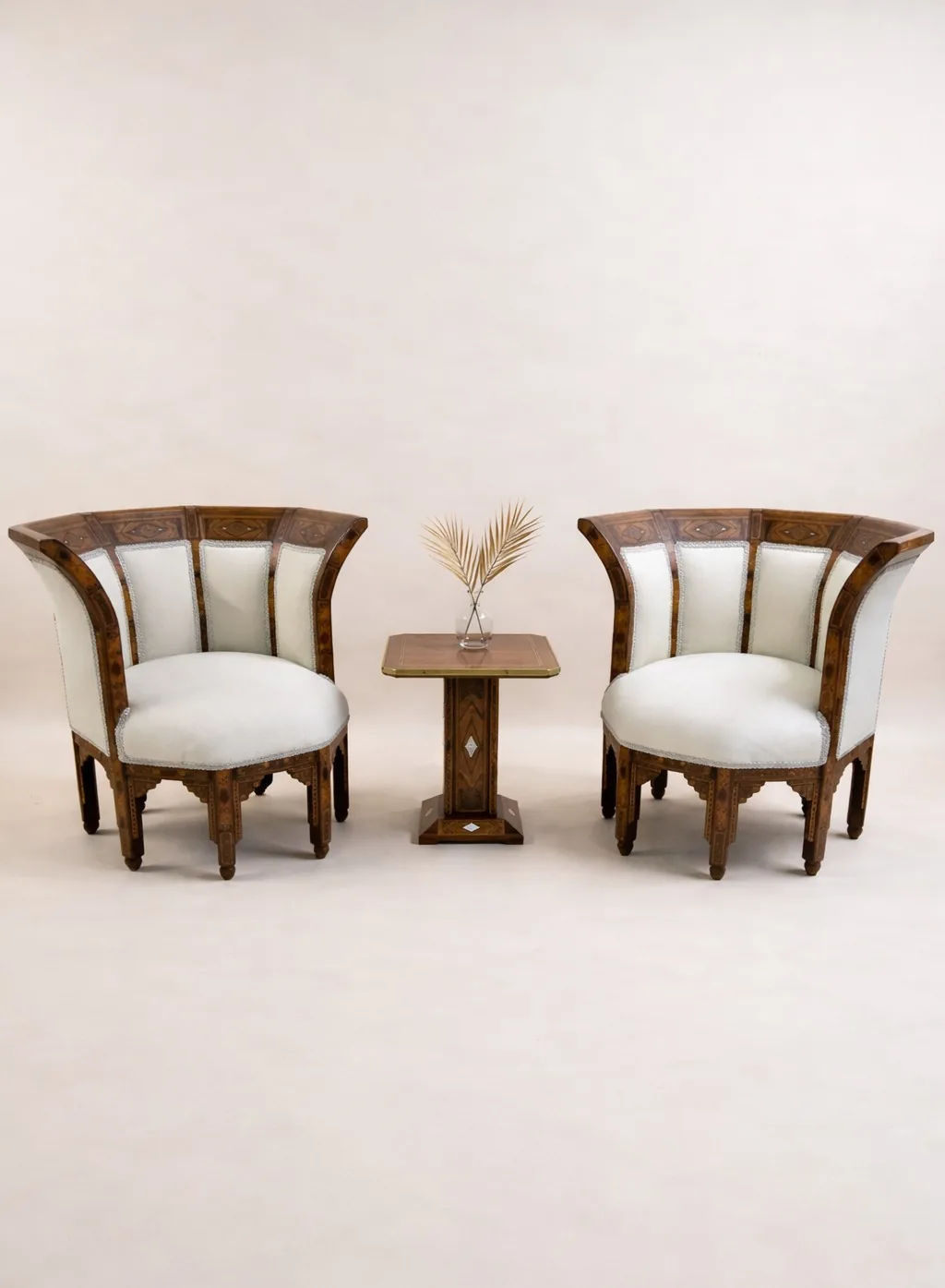 Carved wooden armchairs in cream upholstery with a side table