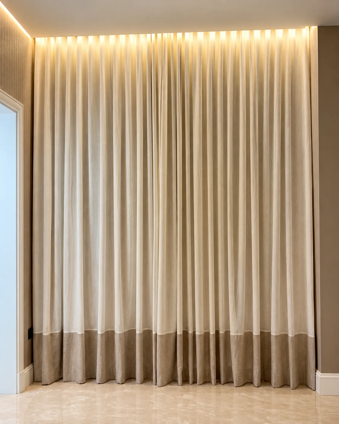 Cream wave curtains with a contrast hem under cove lighting