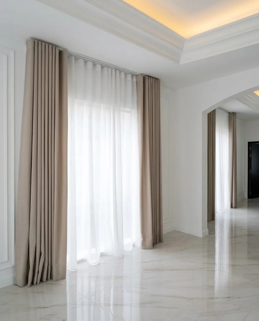 Taupe wave curtains and sheers in a marble-floored hall