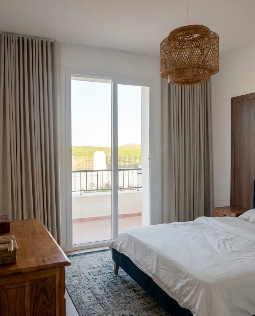 Taupe wave curtains beside a bedroom balcony door