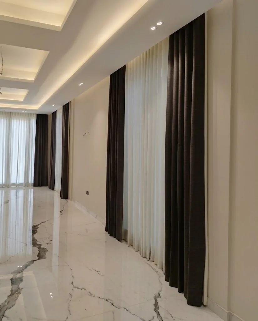 Charcoal wave curtains and sheers along a long marble corridor