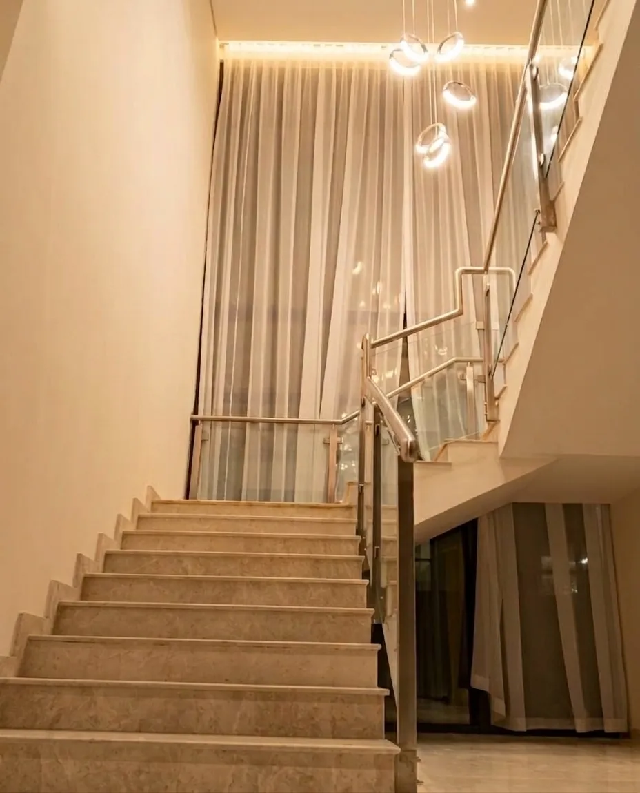 Full-height sheer curtains along a double-height staircase window