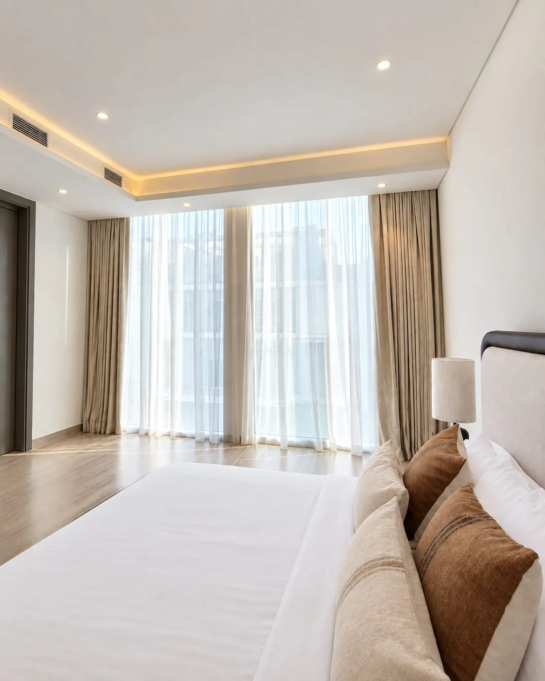 Master bedroom with full-height sheers and taupe side curtains