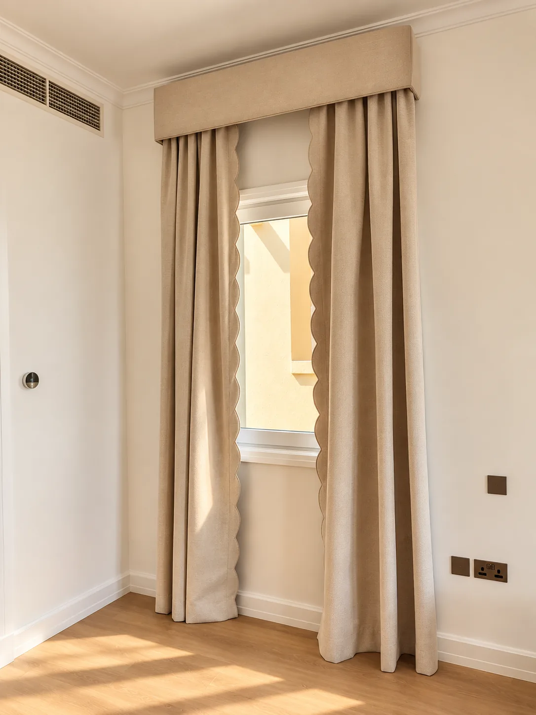 Beige pleated curtains under a fabric pelmet with a scalloped edge